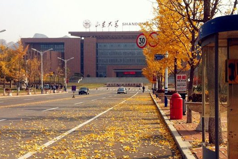 A tree-lined pedestrian route through a spacious campus landscape in autumn.